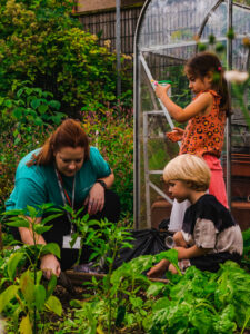 Play leader helping children with bug hunt at kids holiday camp